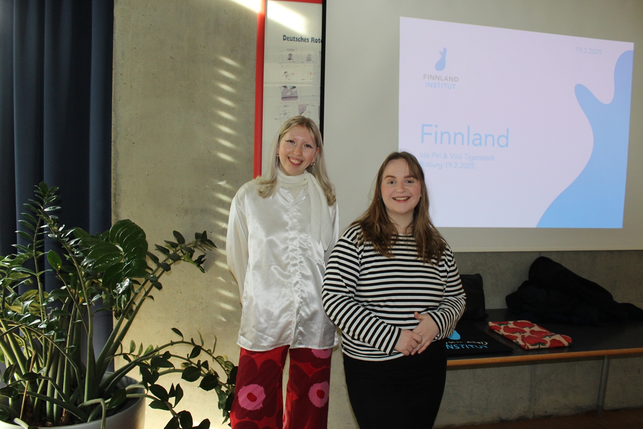 Das Foto zeigt die beiden finnischen Studentinnen Ida und Vilvi vor einer Präsentationswand